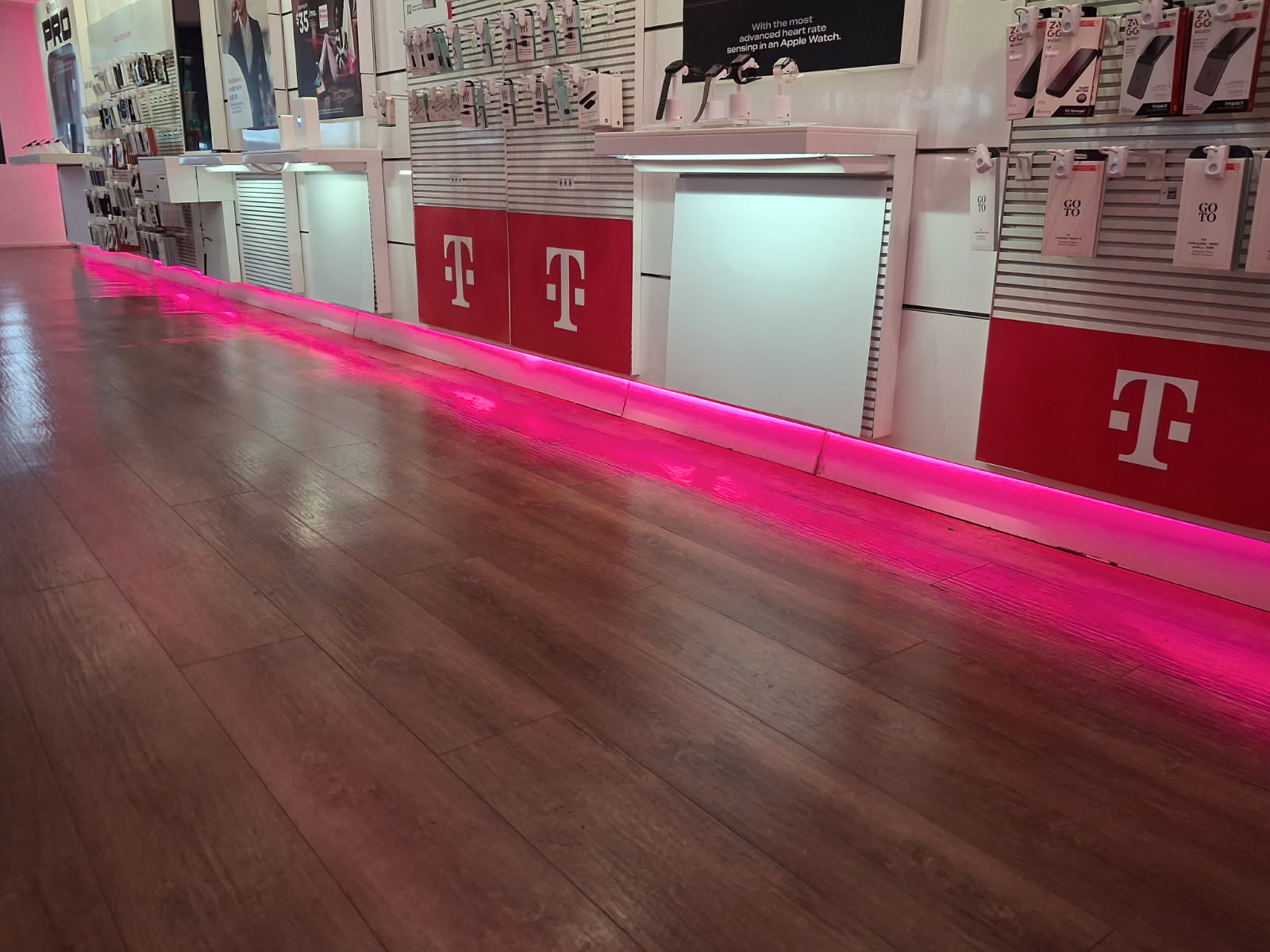 Retail store interior fit out with new wood plank flooring, white wall display panels and accent lighting running along the base of the displays