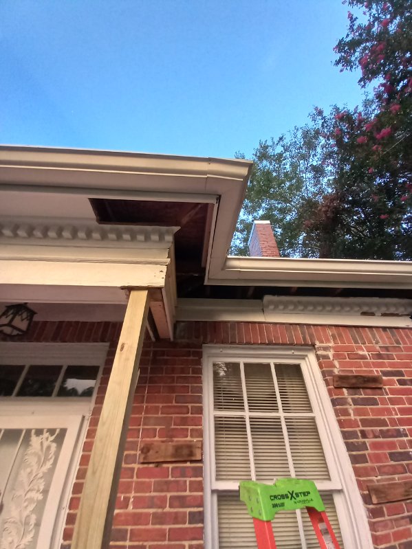 Red brick building with a damaged white-trimmed overhang propped on a wooden beam, a step ladder standing below the window